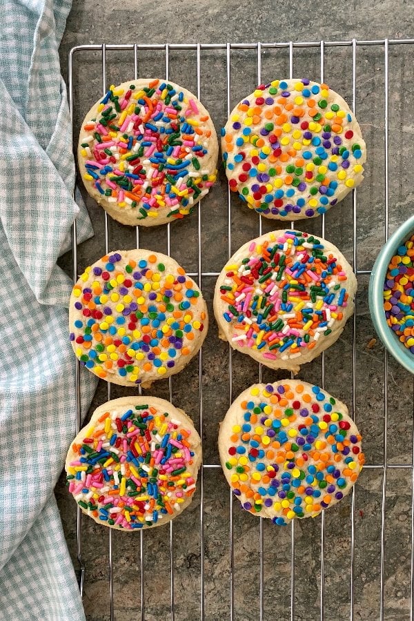 6 sugar cookies with rainbow sprinkles on a cooling rack