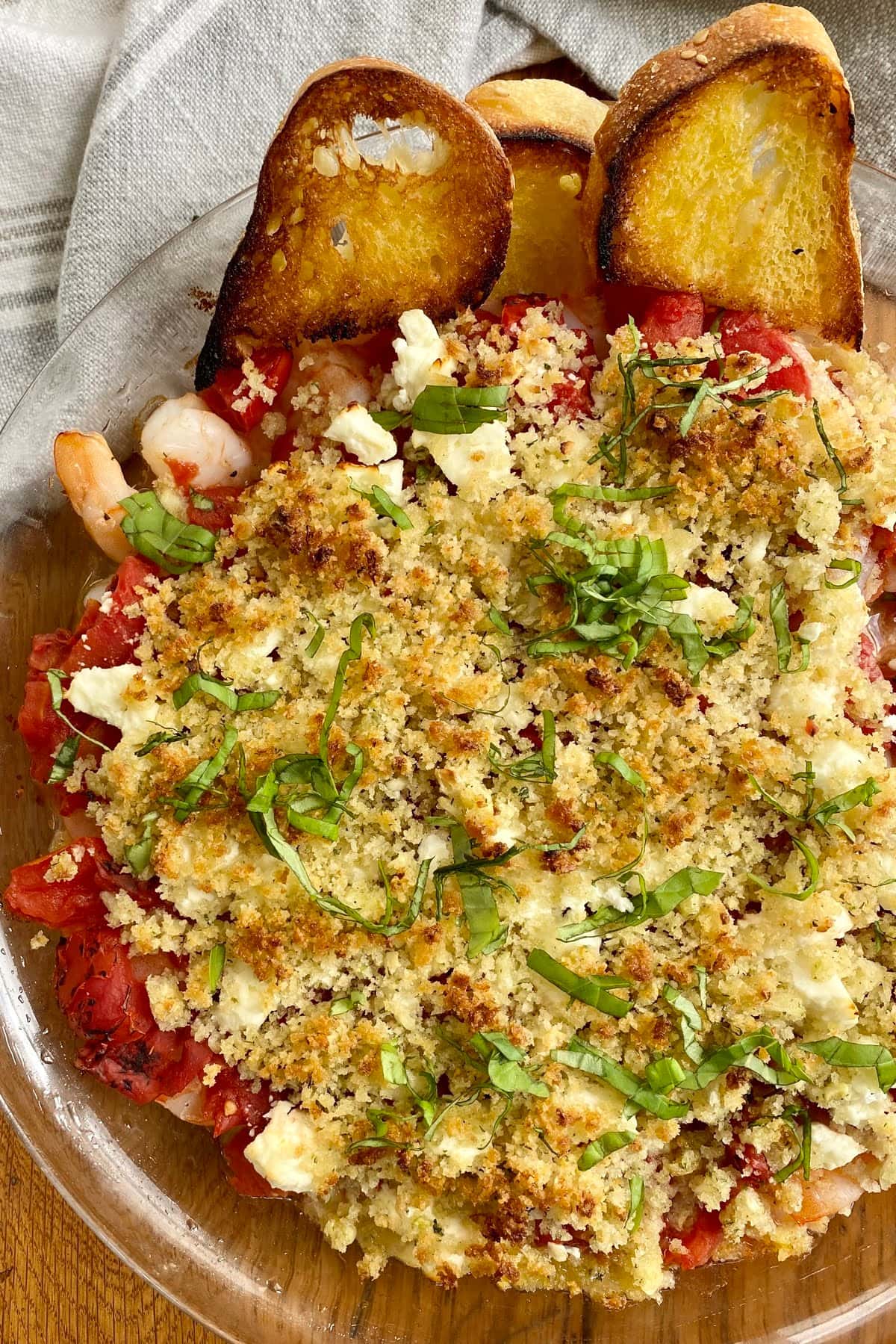 a baked shrimp with feta and tomatoes and crostinis