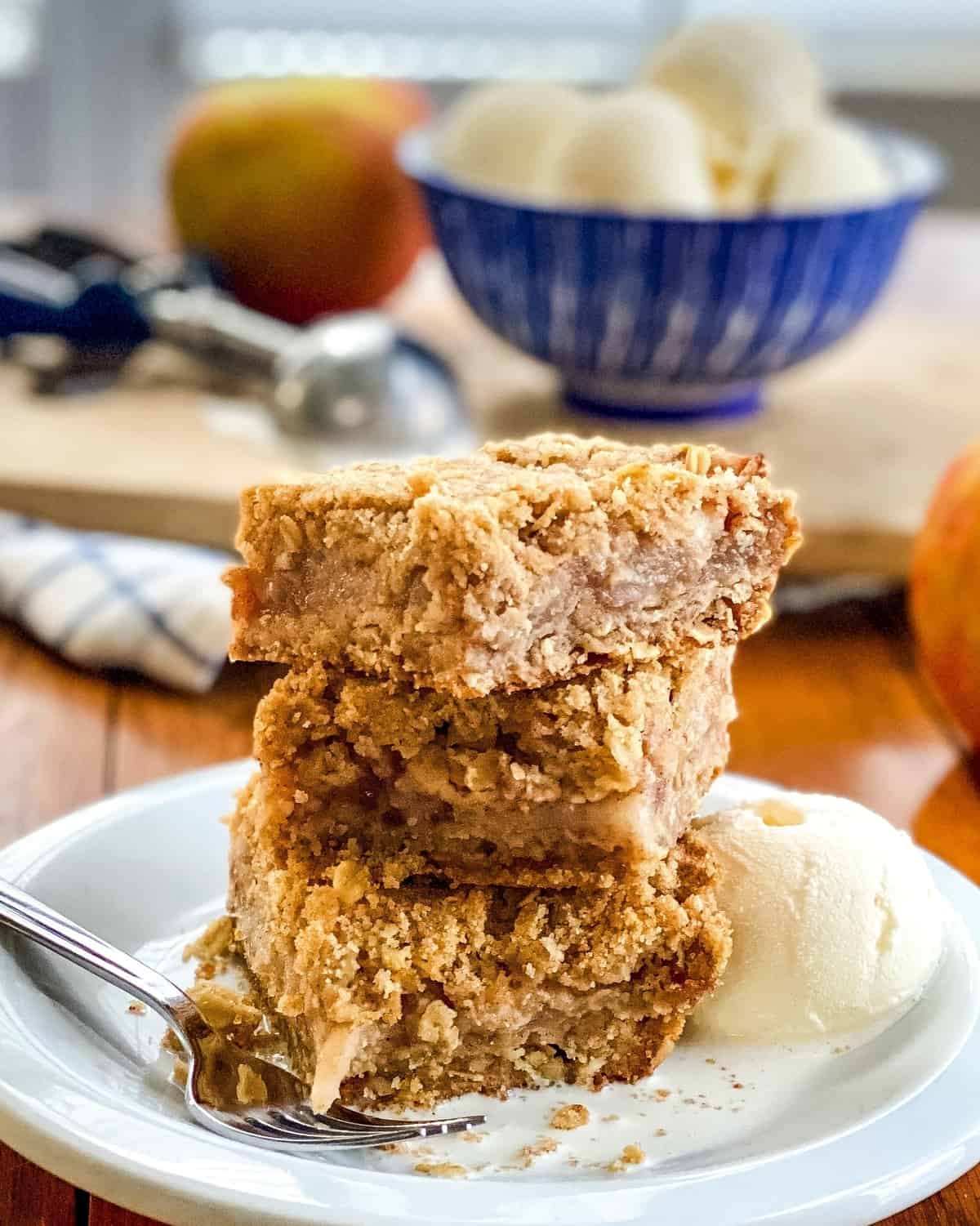 3 apple bars stack on top of each other with vanilla ice cream in the distance