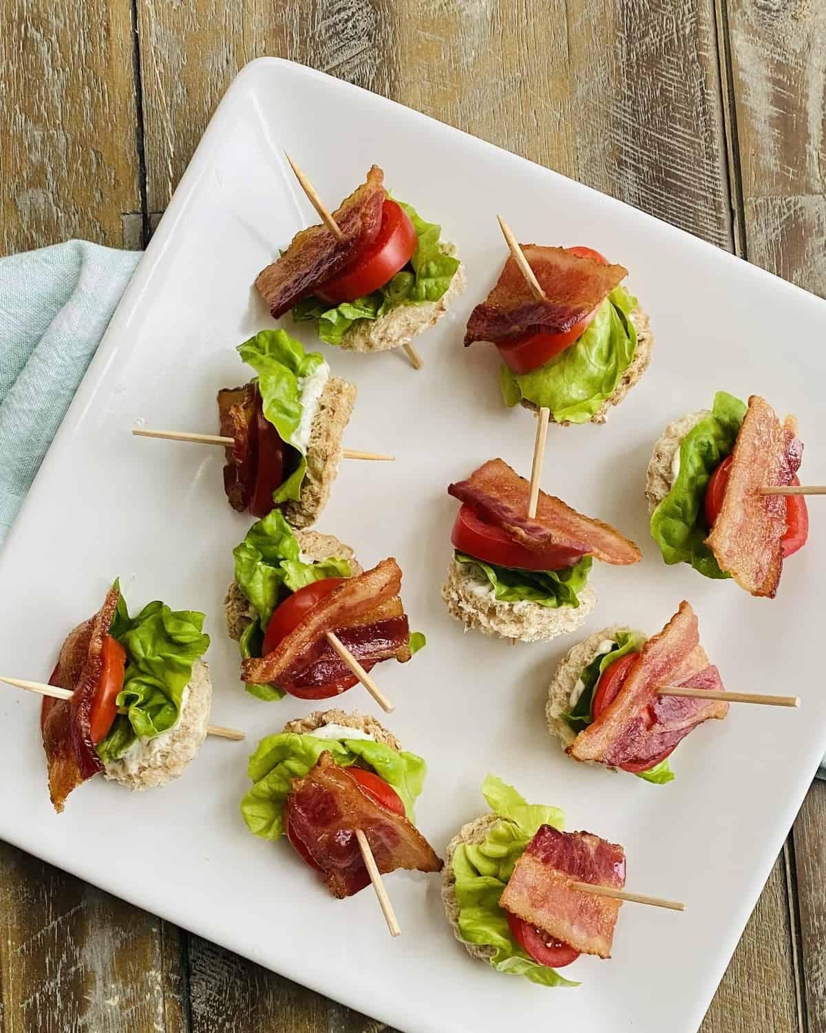 A platter of blt appetizers on toothpicks.