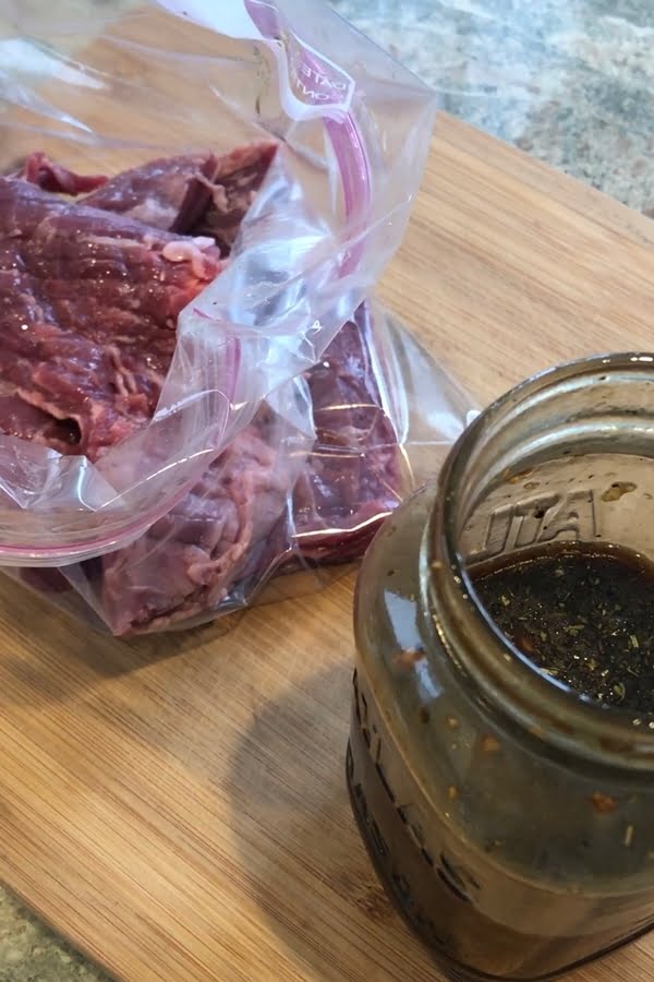 A marinating steak in a resealable bag on a cutting board.