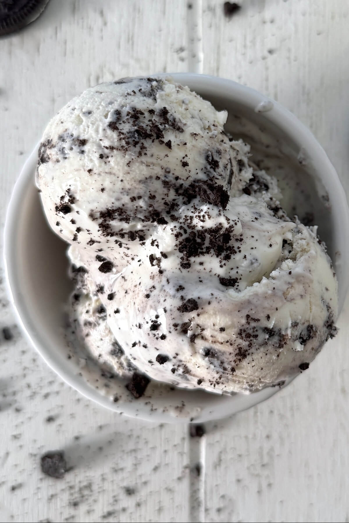 Two scoops for cookies and cream ice cream in a white dish.