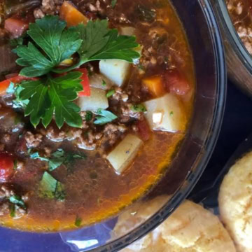 bowl of hearty hamburger soup with cornbread muffins