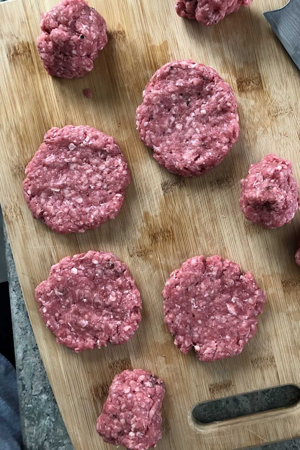 uncooked burgers on a cutting board