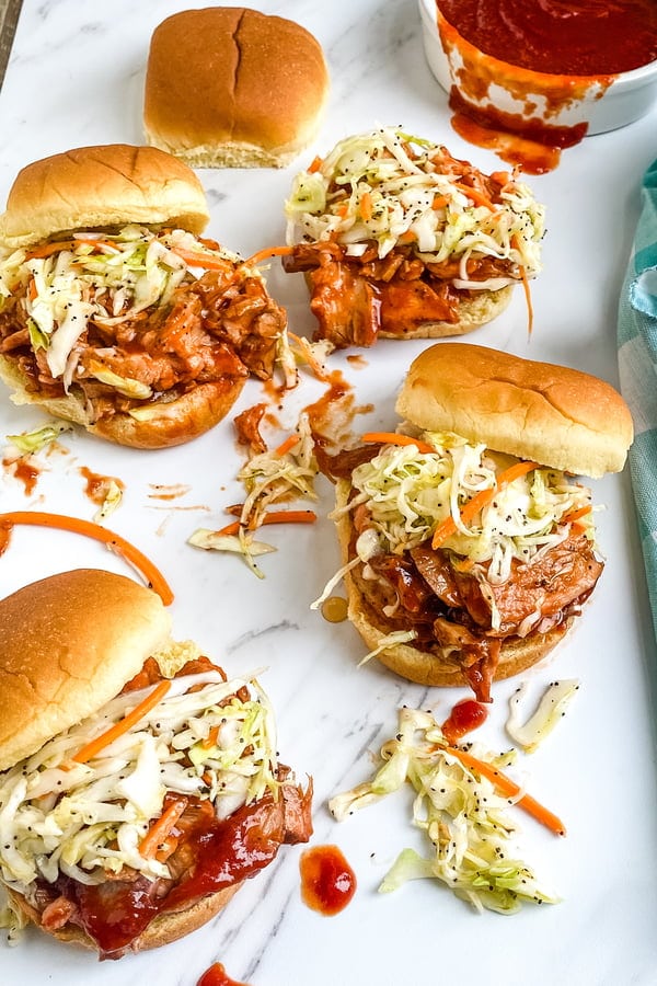 A platter of barbecue pork sliders with cole slaw.