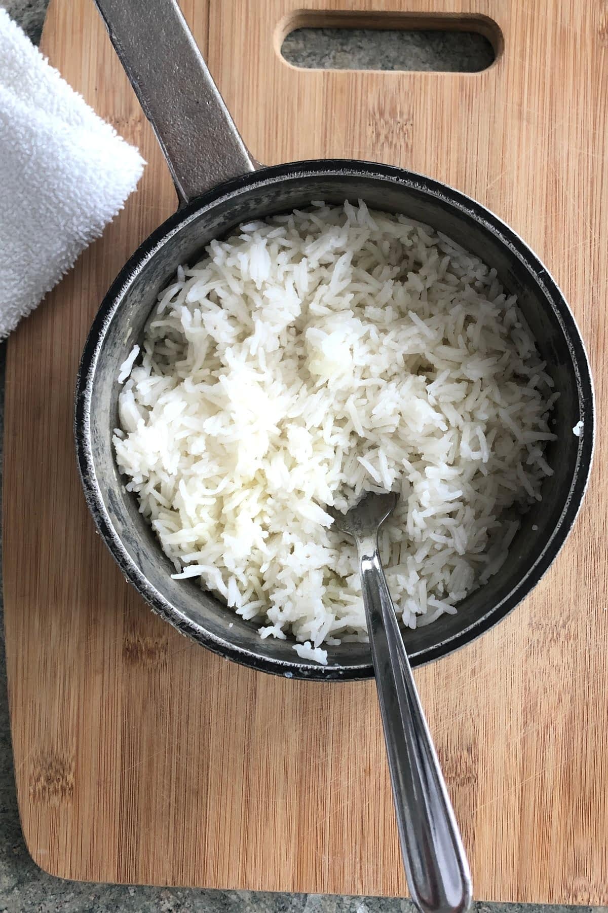 a pot of cooked white rice with a spoon in it.