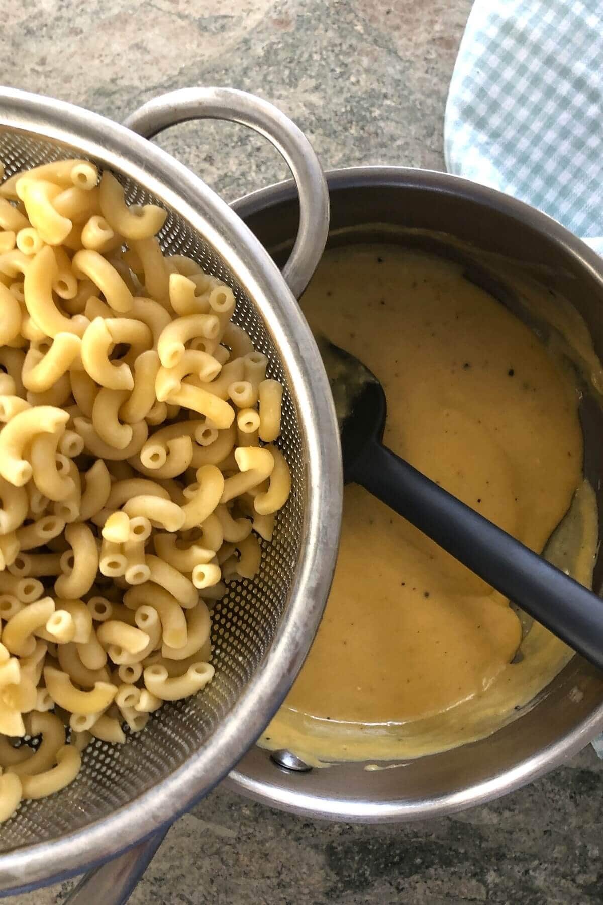 adding elbow pasta to cheese sauce for macaroni and cheese bites.