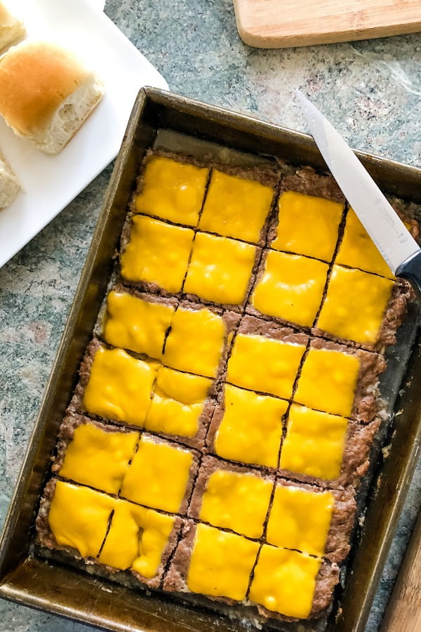 cheeseburger sliders recipe tops a large patty with melted cheese before cutting into small burgers
