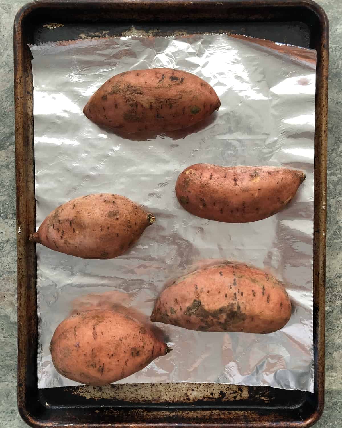 sweet potatoes on a foil lined baking sheet ready to be baked
