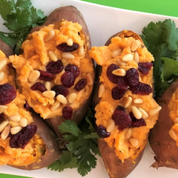 platter of coconut stuffed sweet potatoes topped with dried cranberries and pine nuts