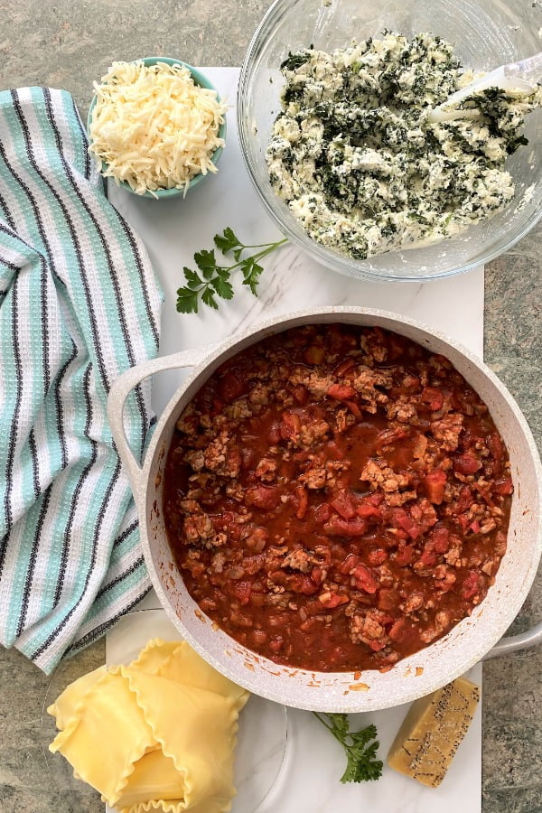 ingredients for making an Italian pasta recipe - 3 cheese mixtures, tomato sauce, pasta, extra cheese