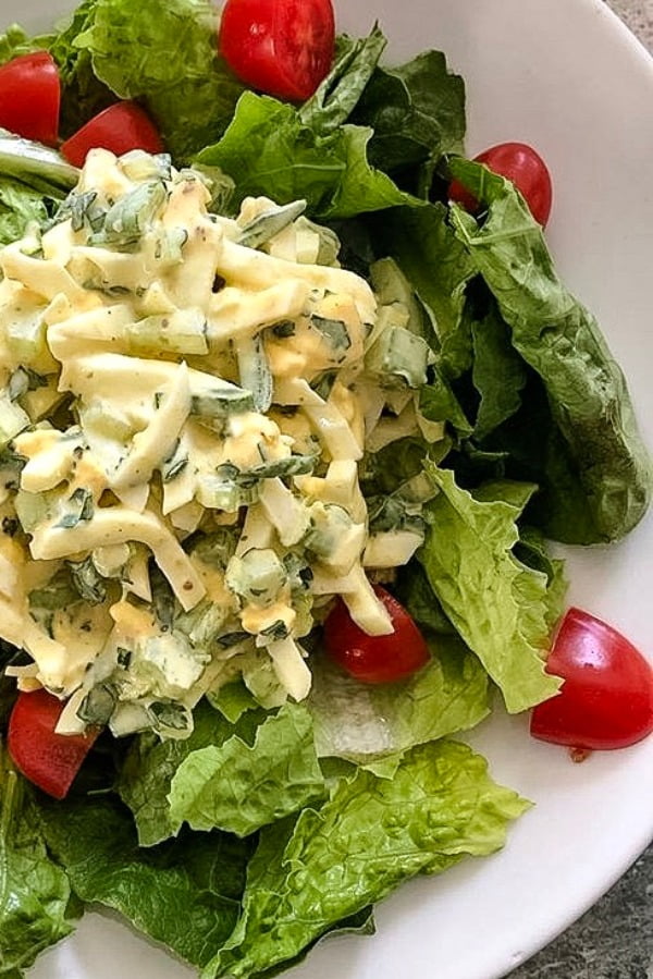 plate of egg salad over greens with cherry tomatoes