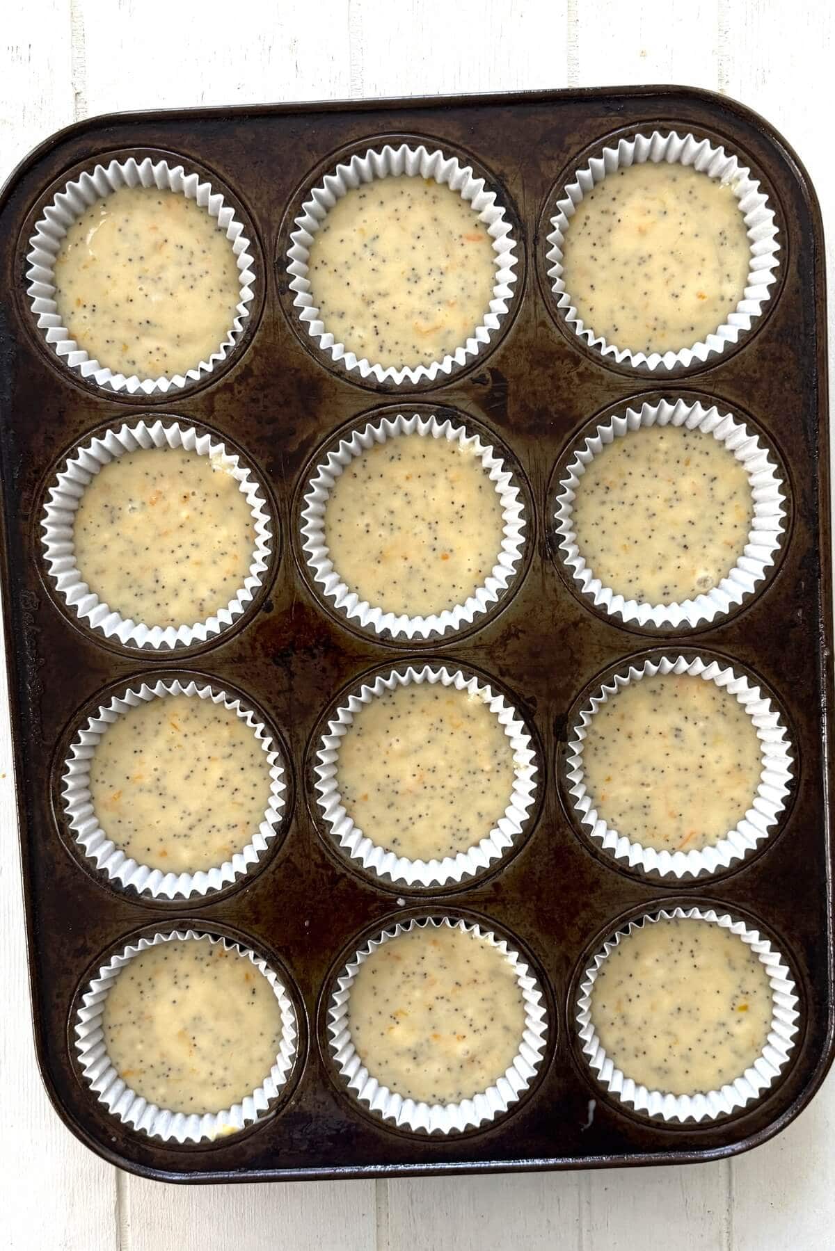 Muffin batter in muffin liners in a pan.