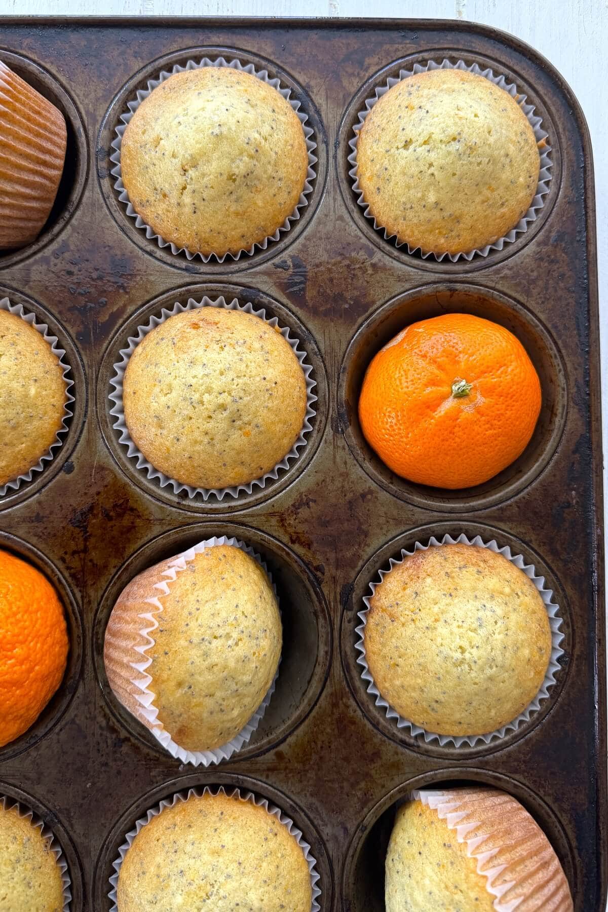 Unglazed orange muffins in a muffin pan.
