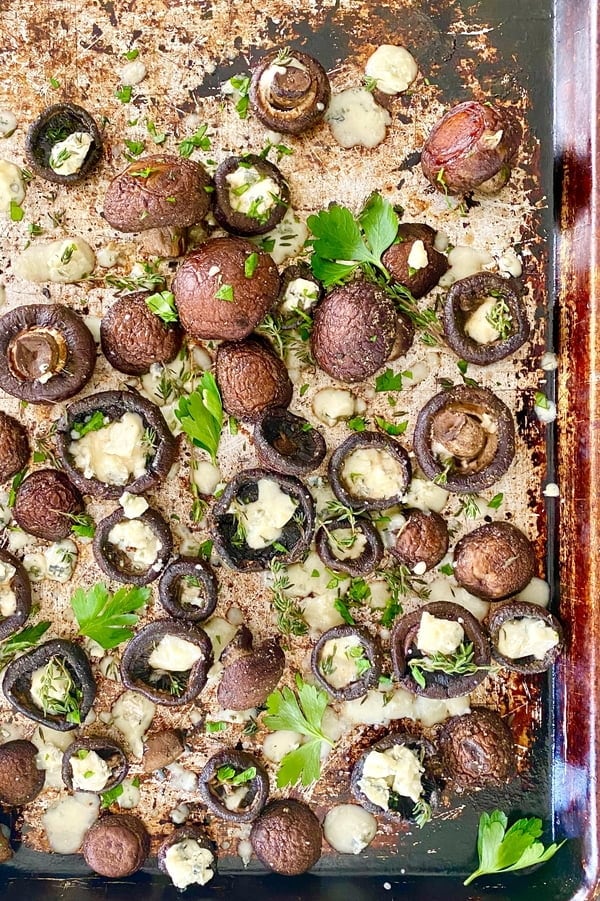 large baking sheet with baked garlic butter mushrooms, blue cheese and fresh herbs