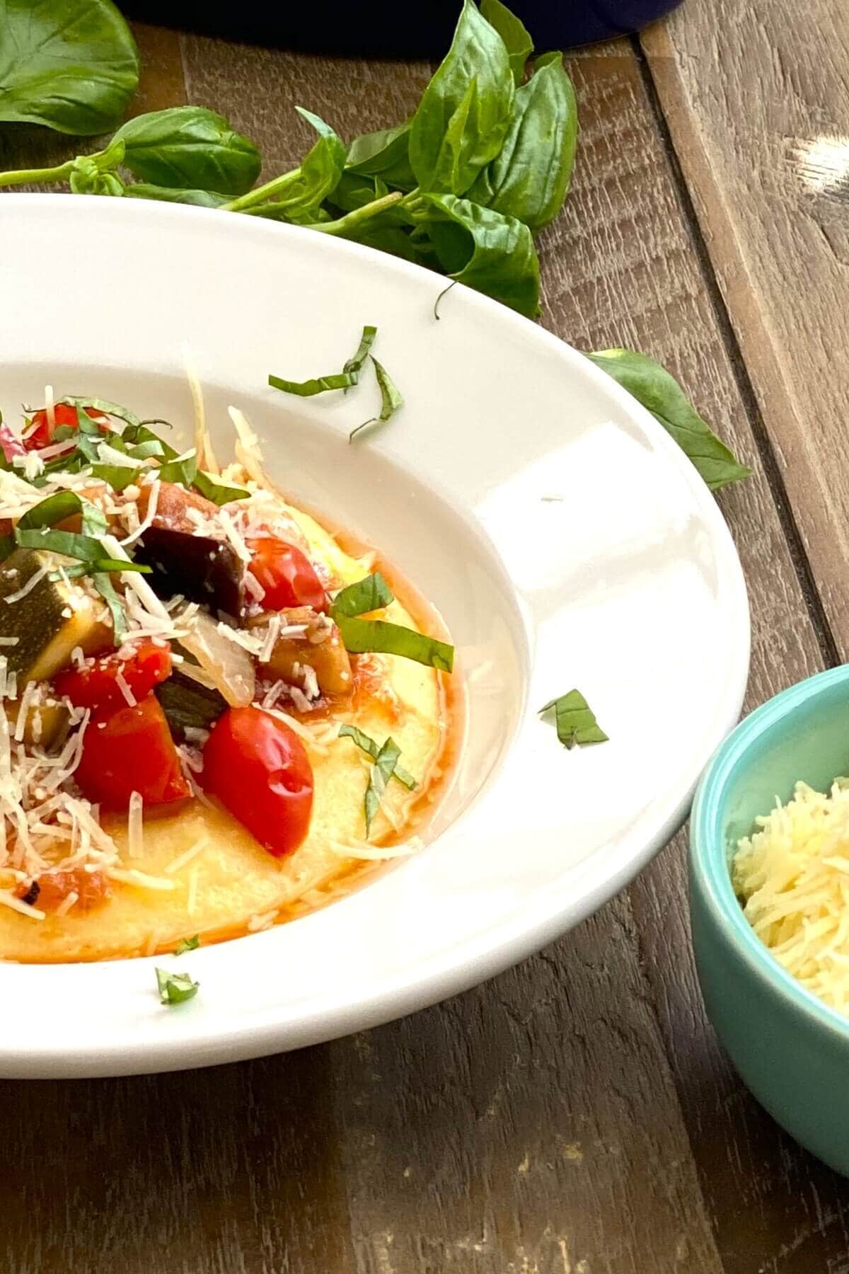 A dish of ratatouille with polenta, fresh basil and parmesan.