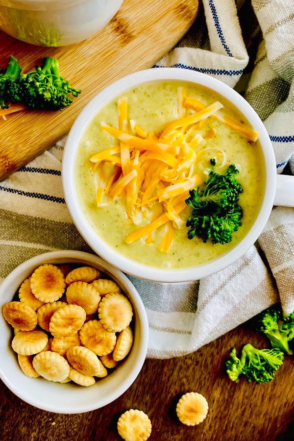 cup of broccoli and cheese soup with oyster crackers