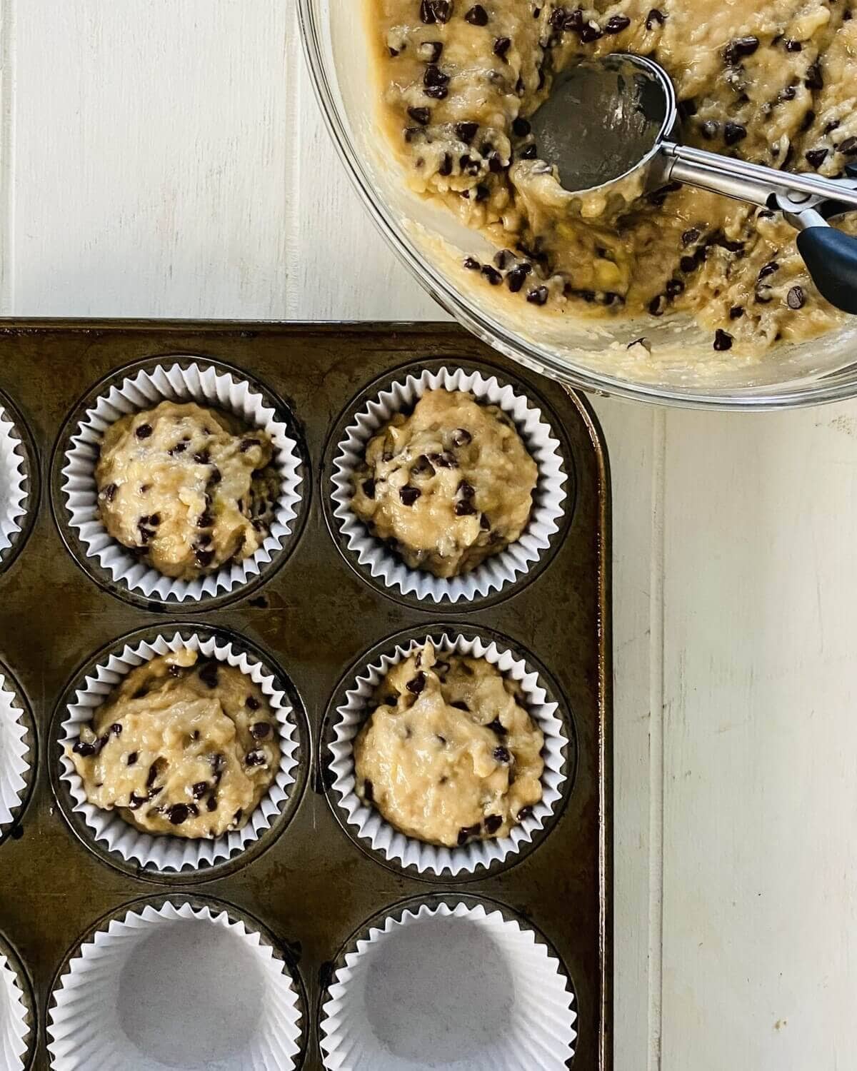 adding banana muffin batter to muffin pan with liners.