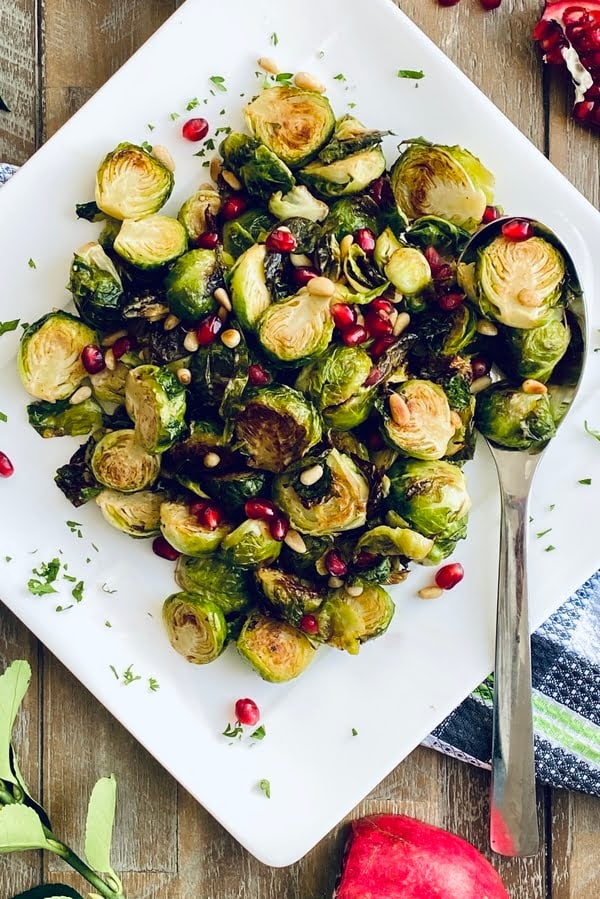 plate of roasted Brussels sprouts with pine nuts and pomegranate arils