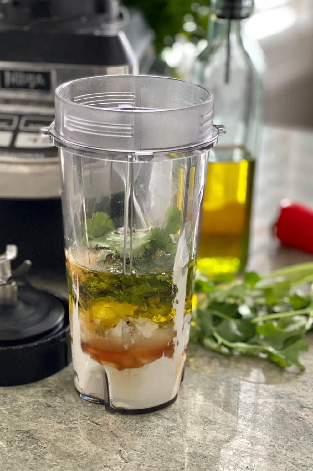 blender with the ingredients for cilantro lime dressing