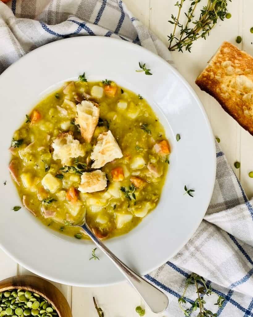 A large bowl of split pea soup with croutons and a spoon.