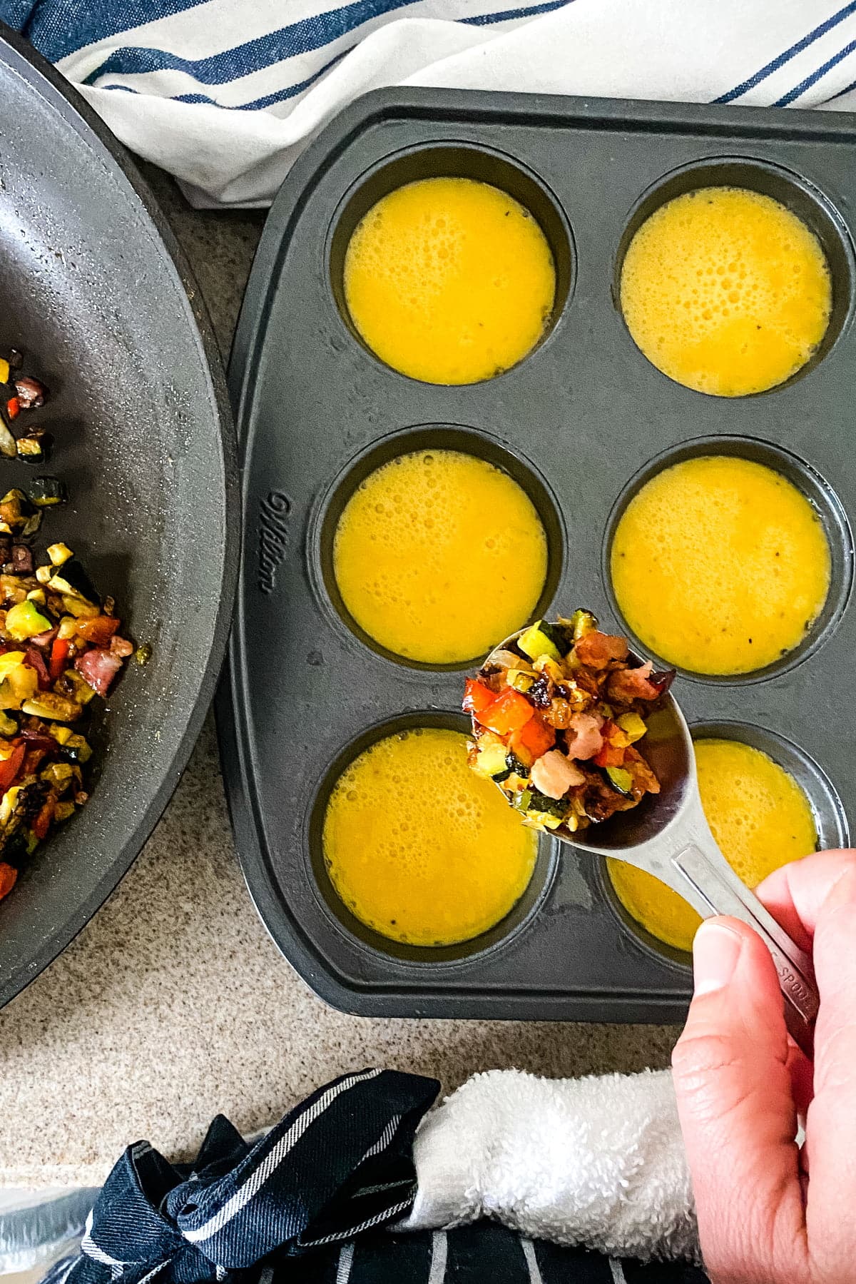 adding sauteed vegetables to beaten eggs for egg cups