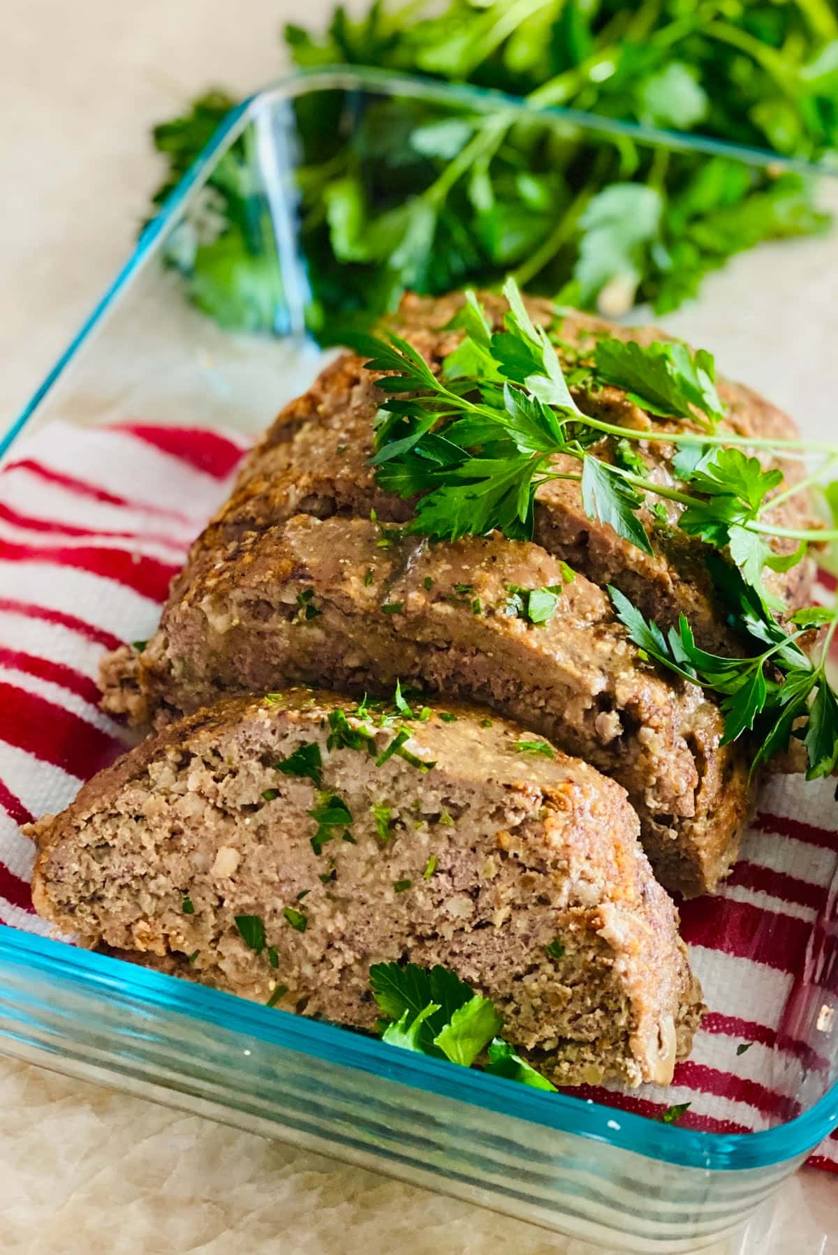 A sliced turkey meatloaf with mushrooms and fresh parsley in a glass dish.