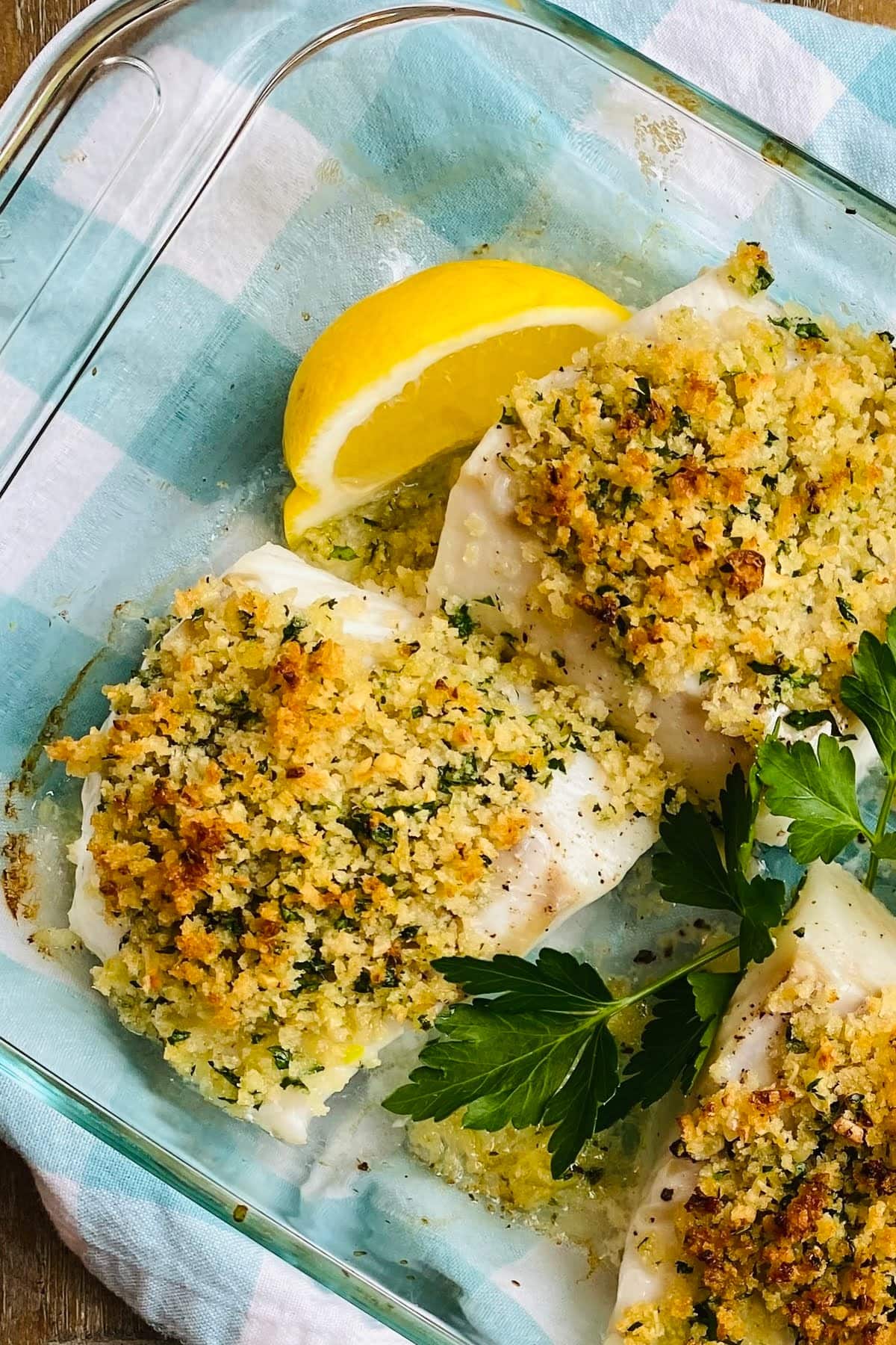 A glass dish with baked cod with garlic panko.