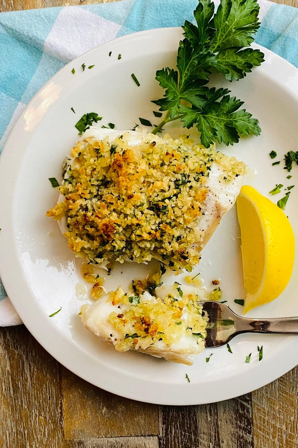 A fork with a piece baked cod with panko.
