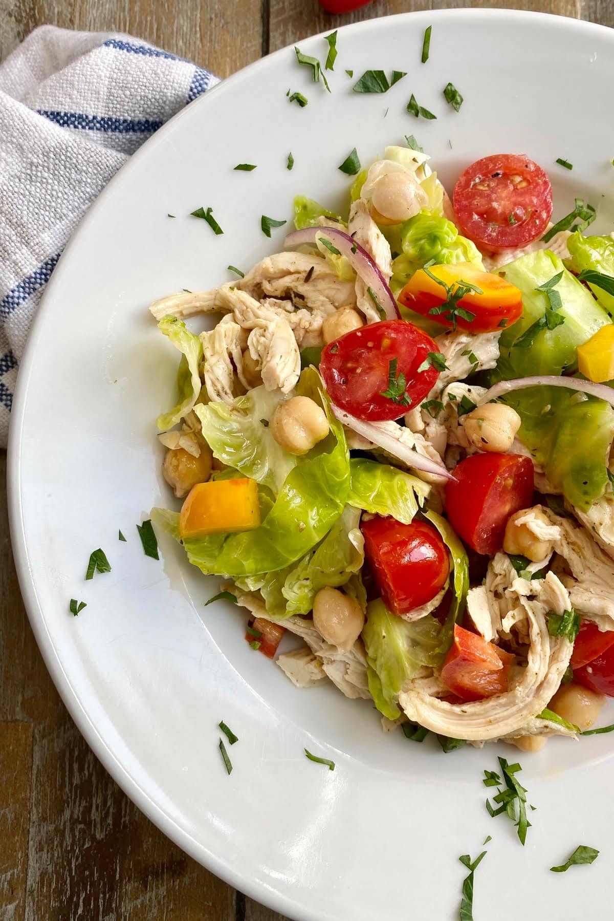 bowl of healthy chicken salad with chickpeas, tomatoes, bell peppers, and Brussels sprouts