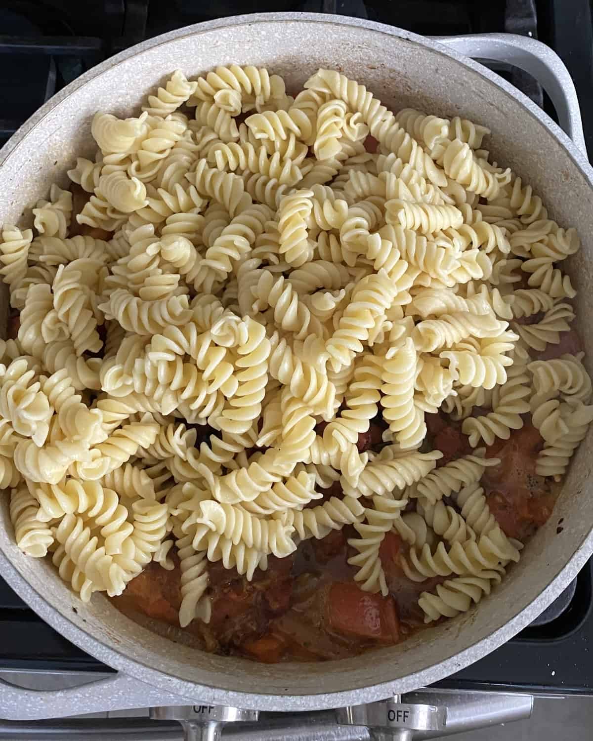 adding cooked pasta to sauce