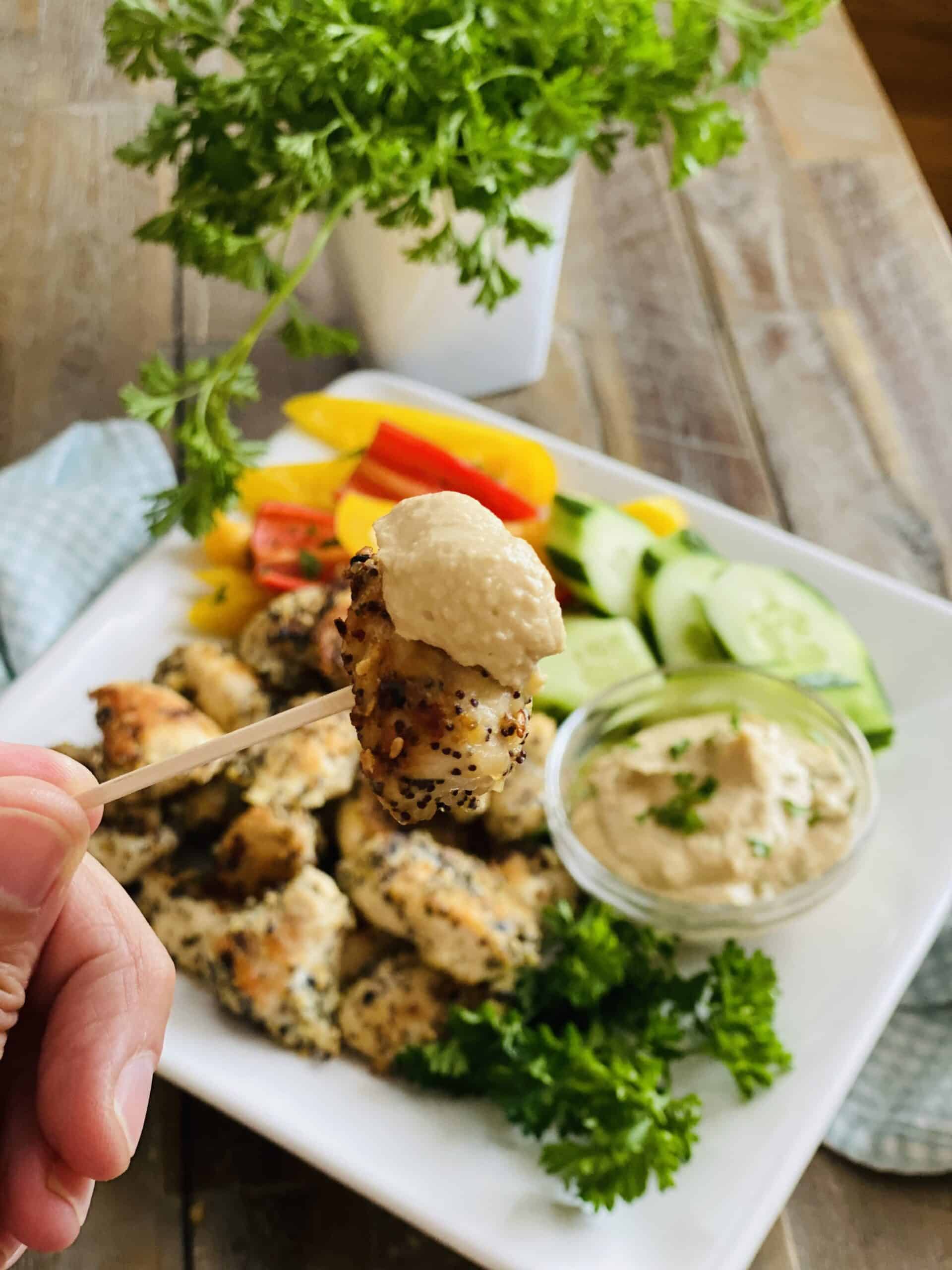 piece of seasoned chicken on a toothpick and dipped in hummus