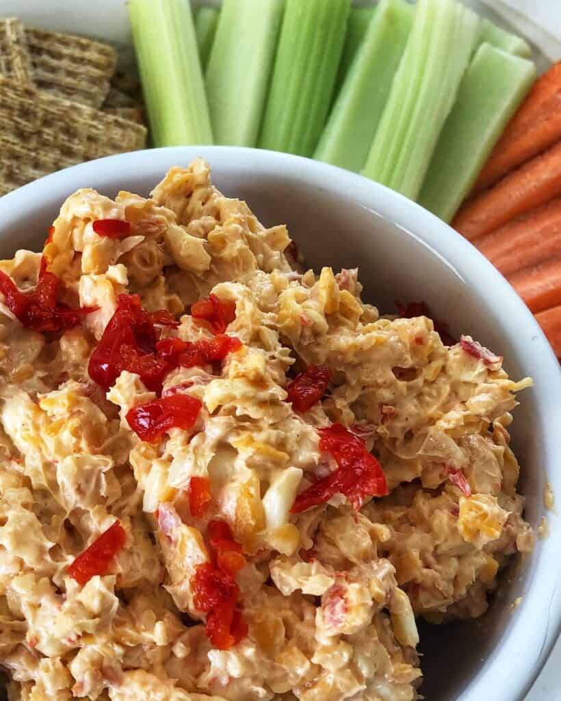 bowl of pimento cheese with carrot and celery sticks and wheat crackers