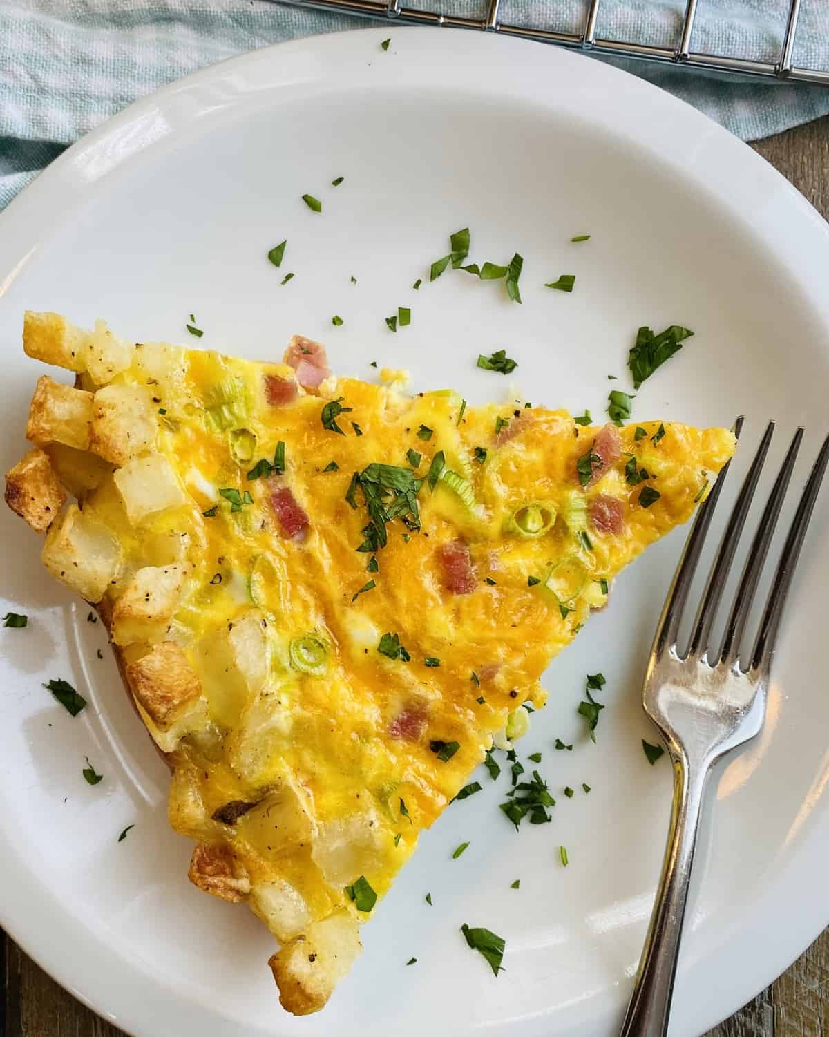 A slice of quiche on a plate with a fork.