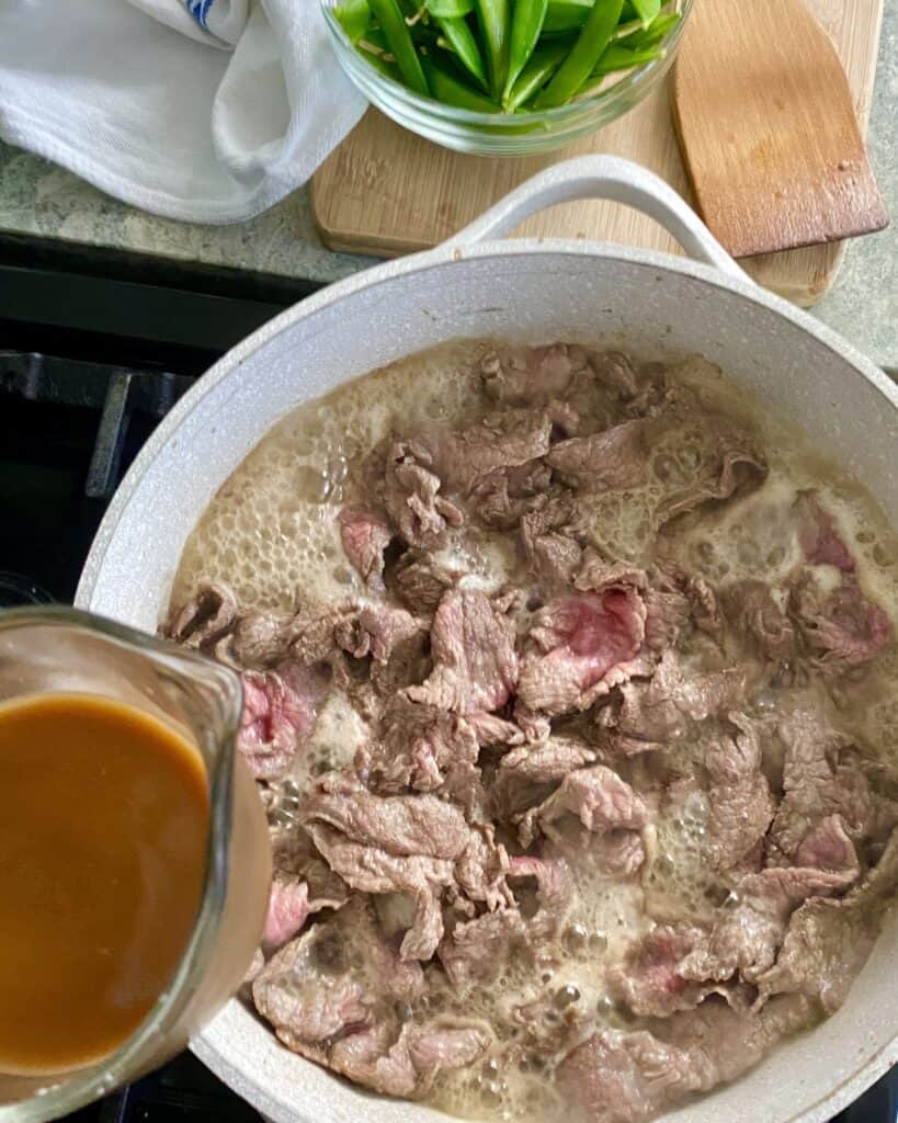 adding sauce to cooked steak for beef stir fry recipe
