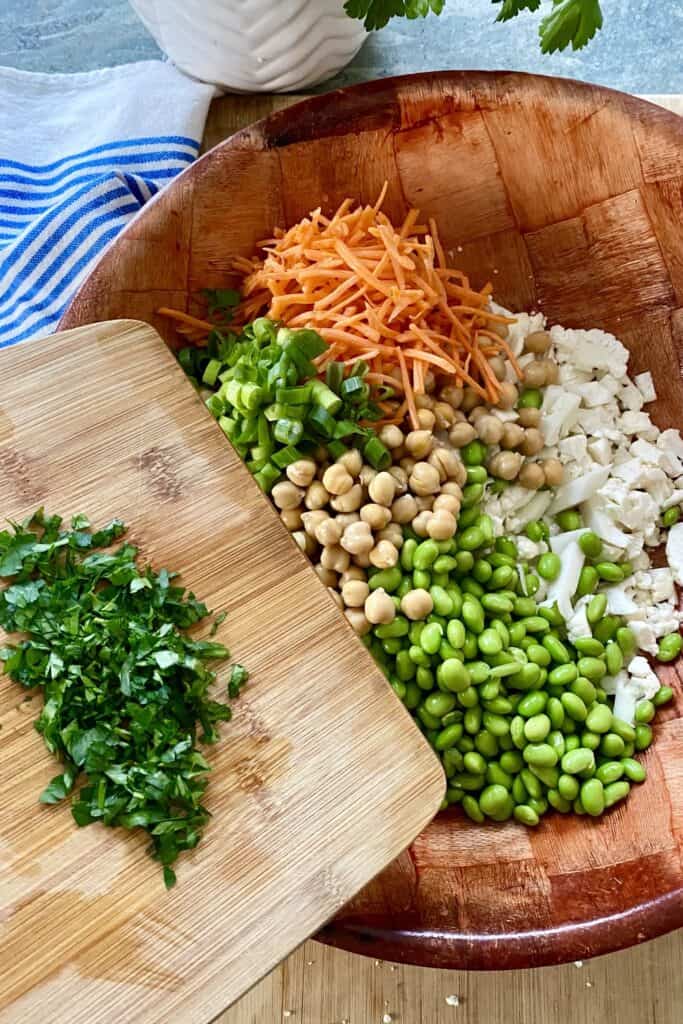 chopped cauliflower, edamame, chickpeas, carrots and parsley for salad in a bowl