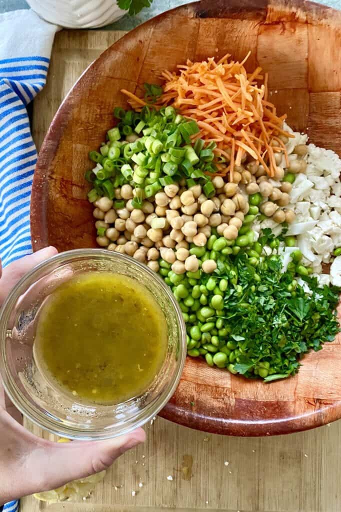 pouring vinaigrette over vegetables for cauliflower salad
