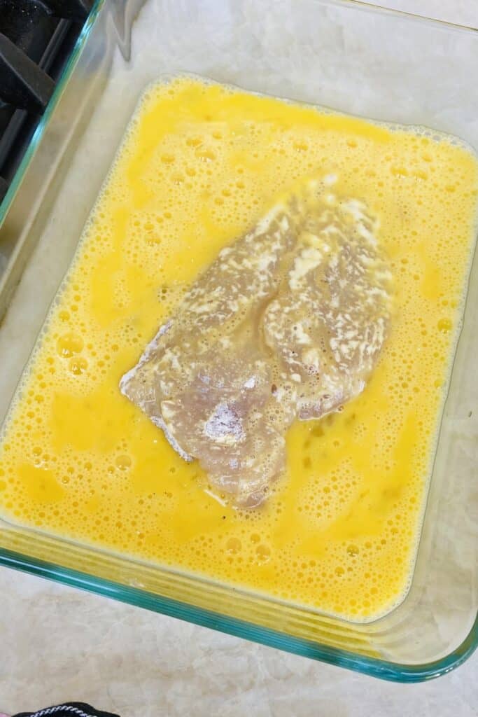 Dipping floured chicken in egg wash.