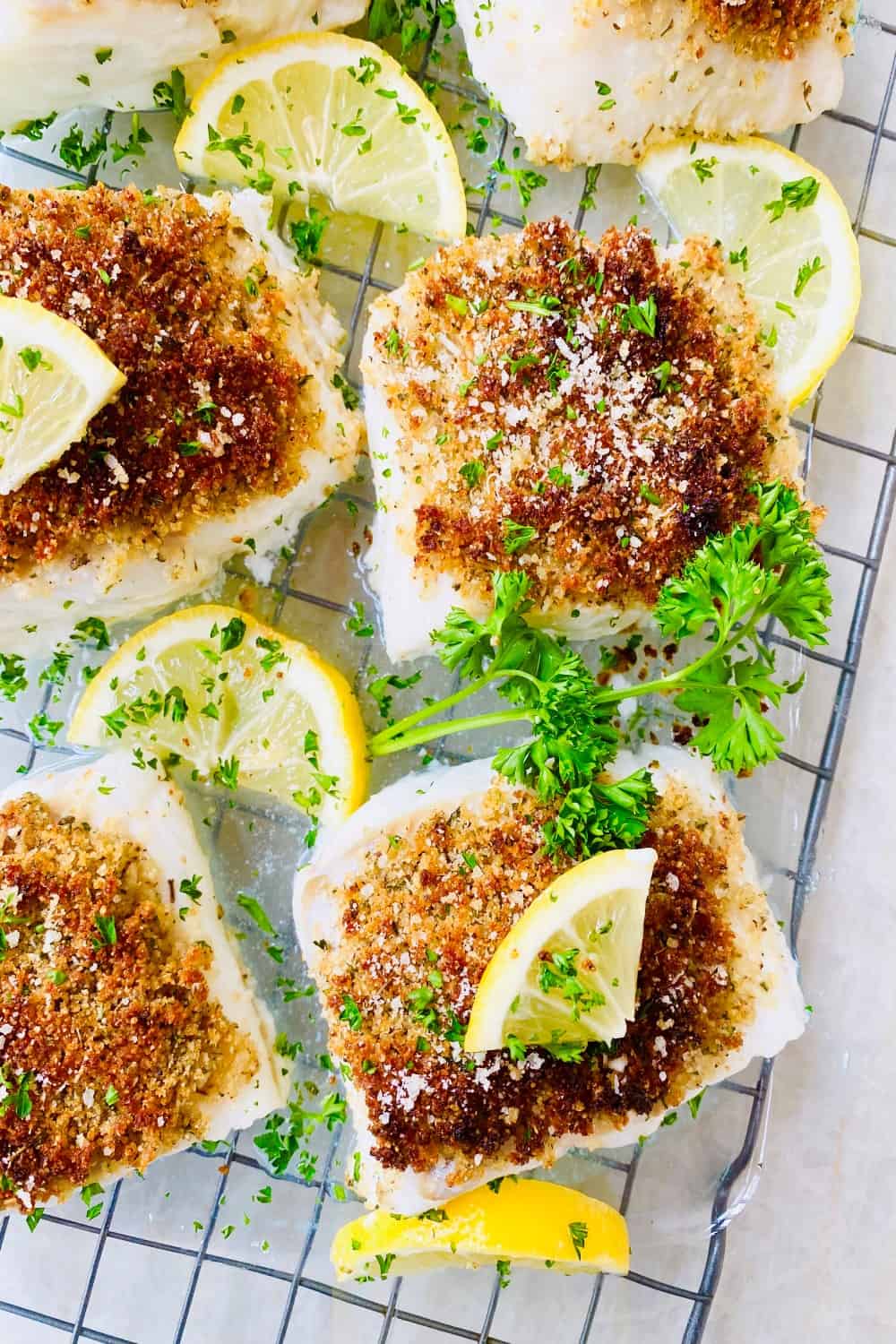 4 pieces of oven baked cod oreganata with lemon slices.