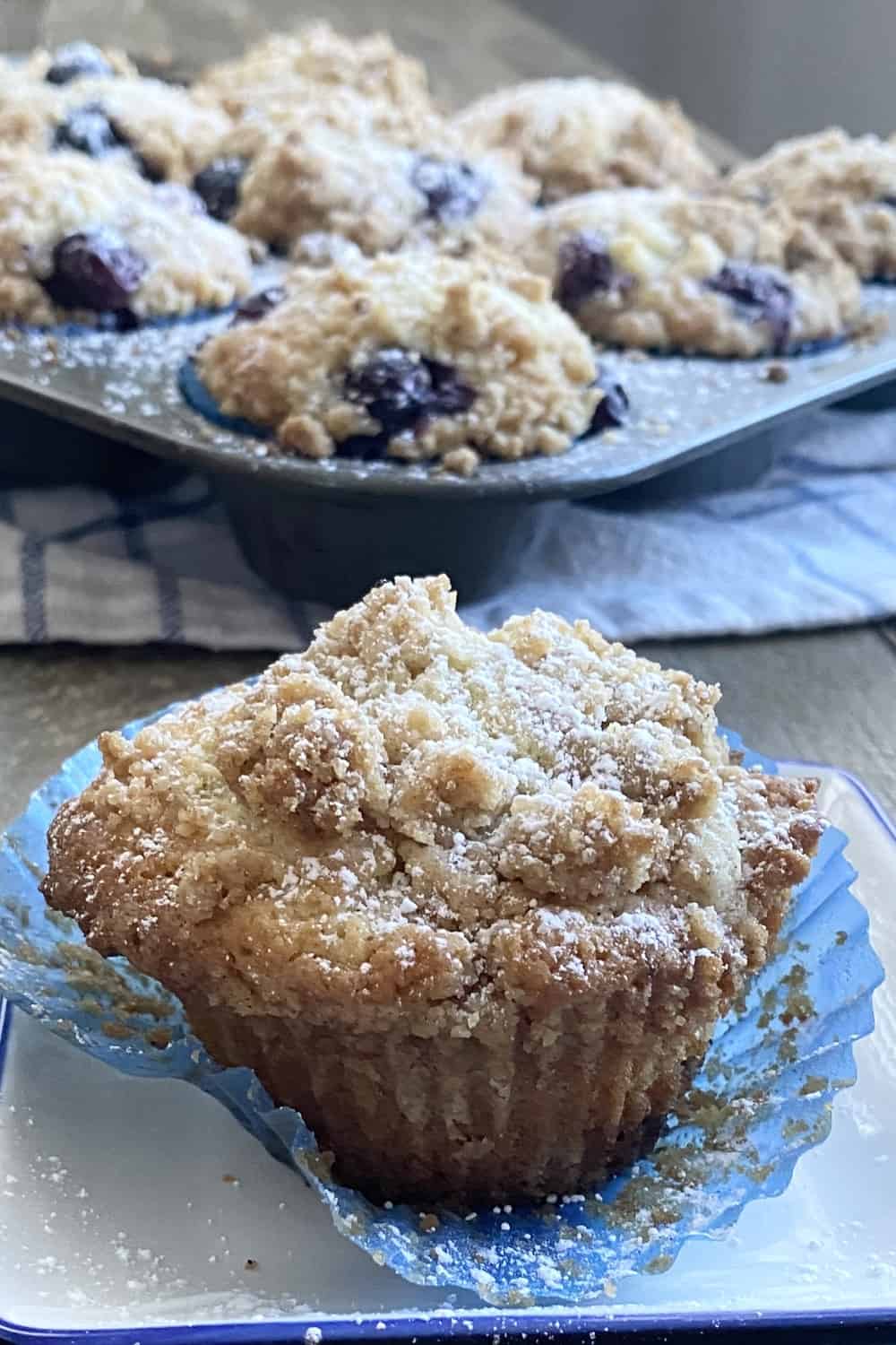 Coffee cake muffins in a muffin tin and one on a plate.