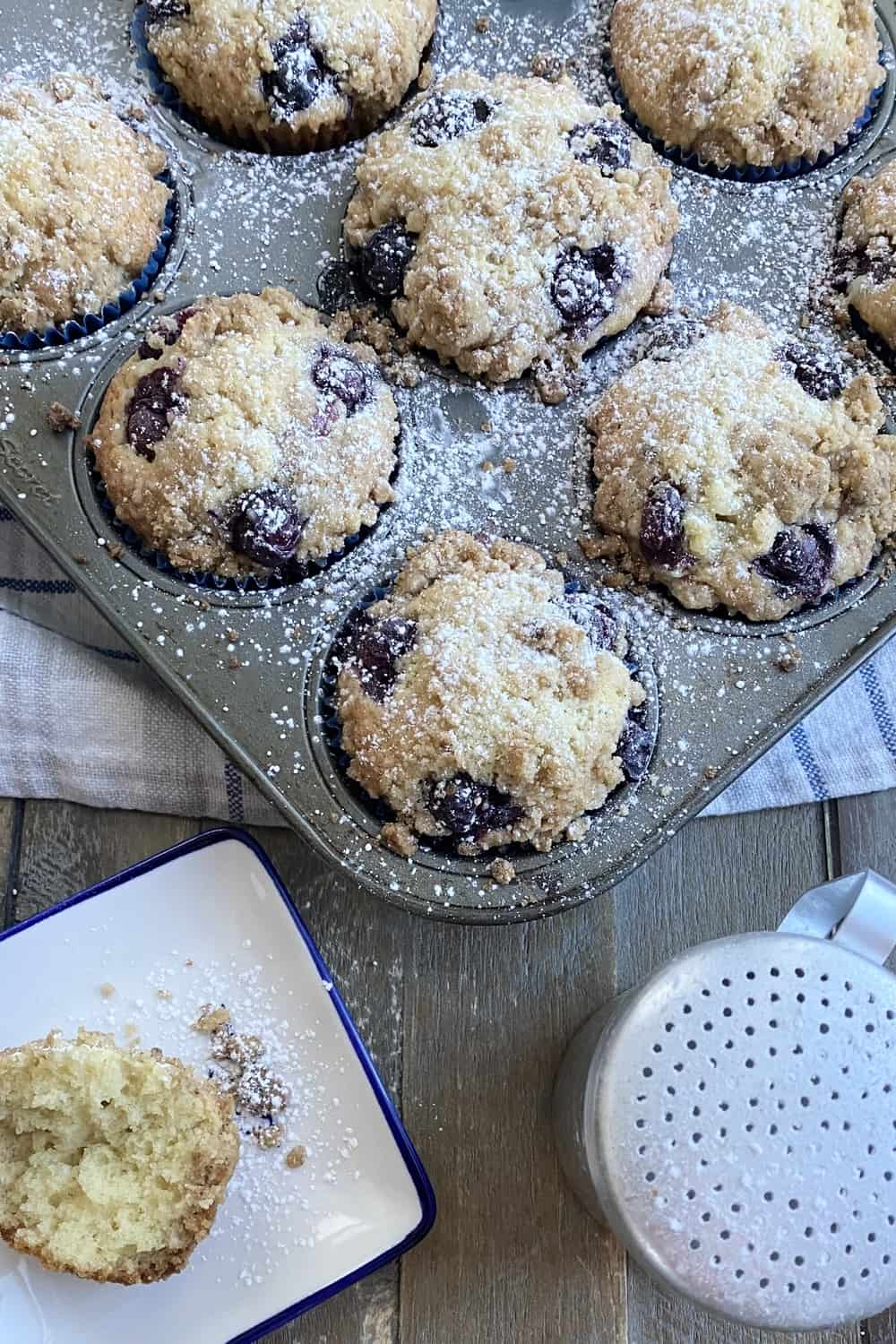 A pan of muffins and a powdered sugar shaker.