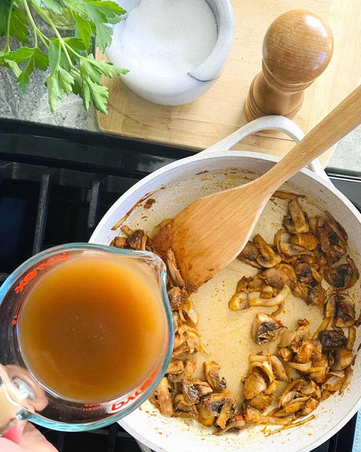 Adding beef broth to stroganoff gravy.