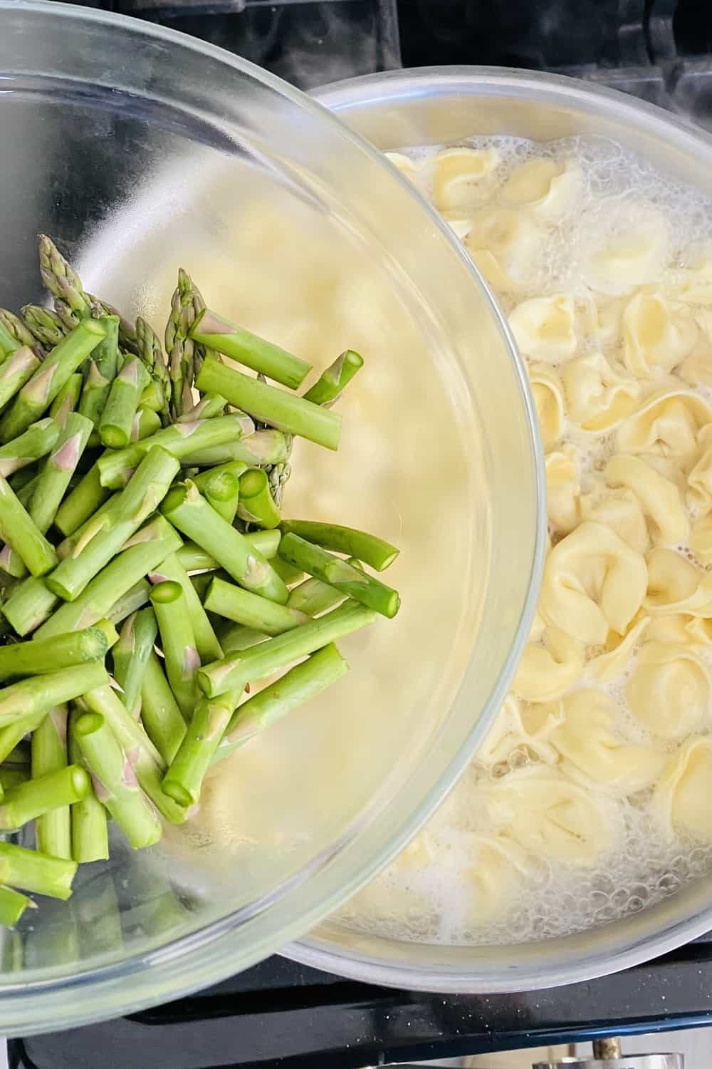 adding asparagus to cooking tortellini pasta