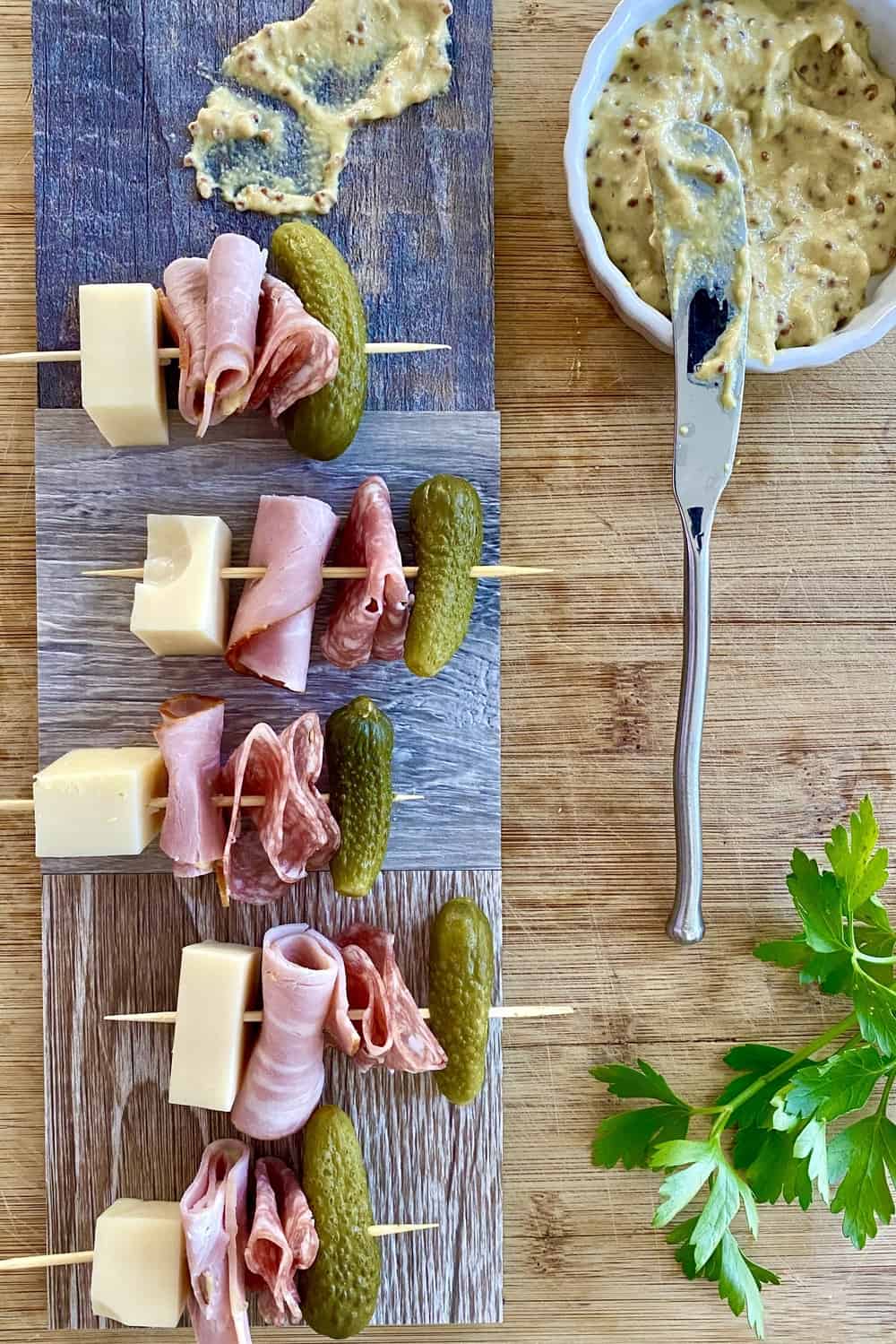 Cuban sandwich appetizer skewers with ham, Swiss cheese, salami and dill pickle.