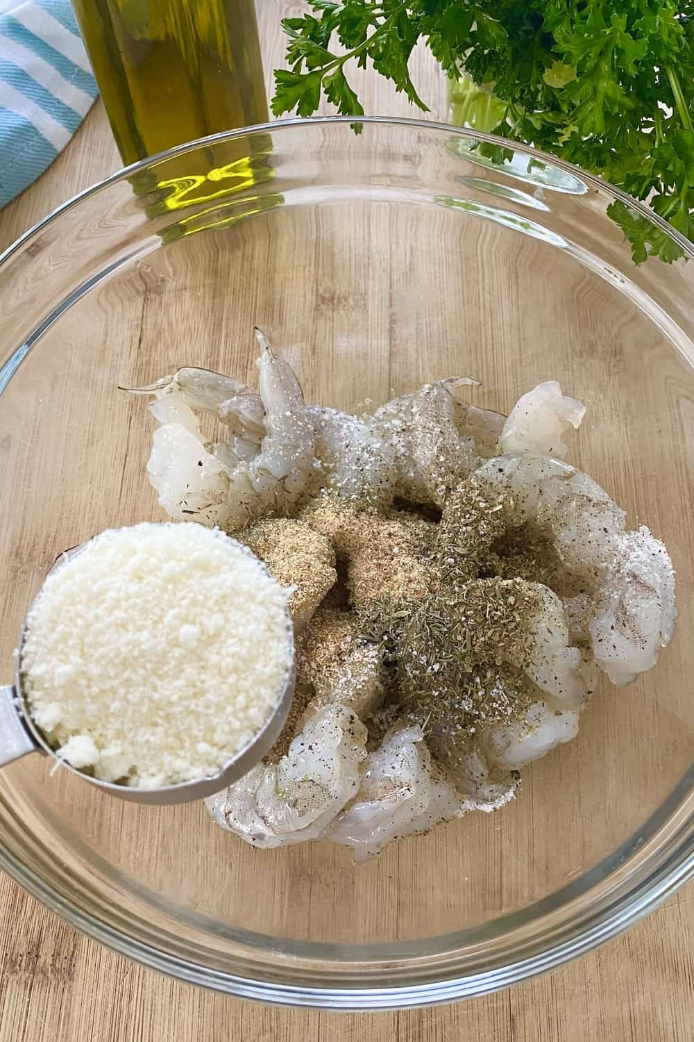 Adding grated parmesan cheese to seasoned shrimp.