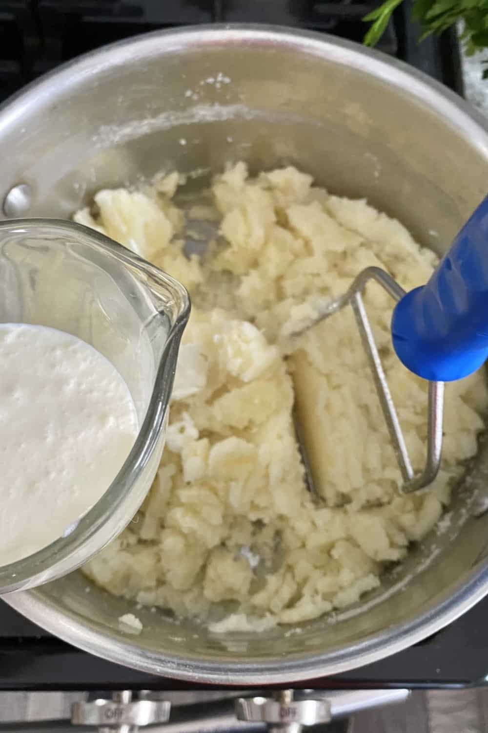Adding heavy cream to partially mashed potatoes.