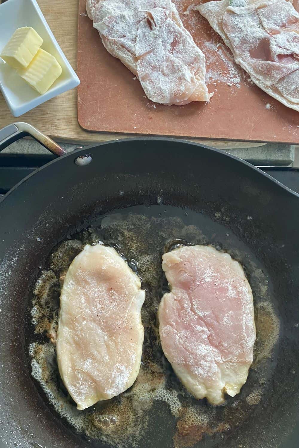 A sauté pan with chicken cooking in it.