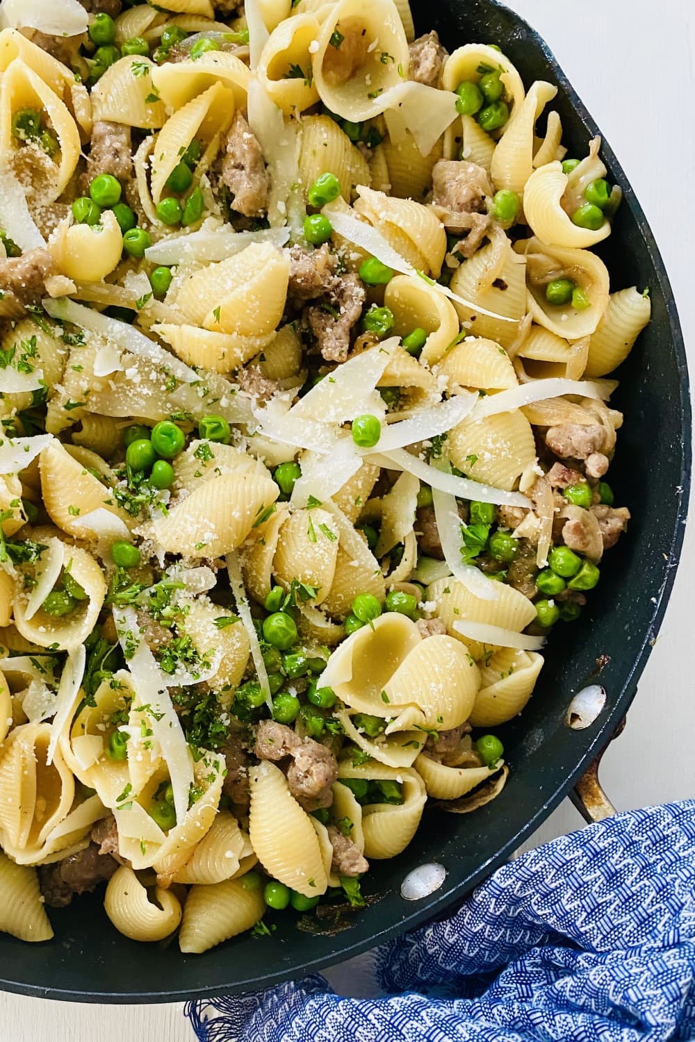 A large sauté pan of pasta and peas and topped with Parmesan cheese.