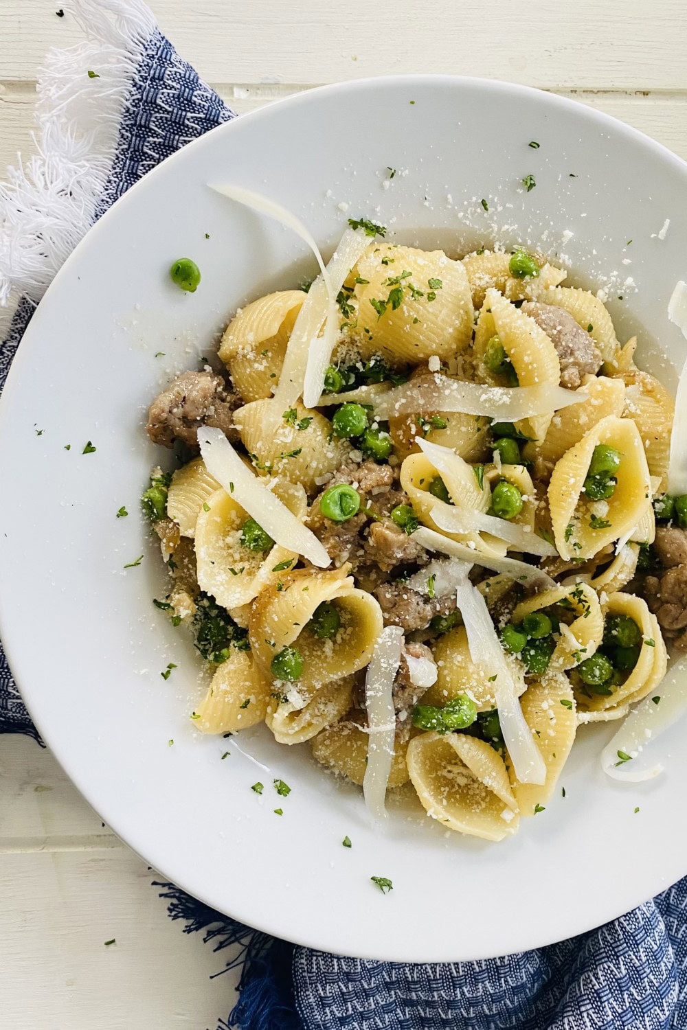 A bowl of pasta and peas with shaved Parmesan.