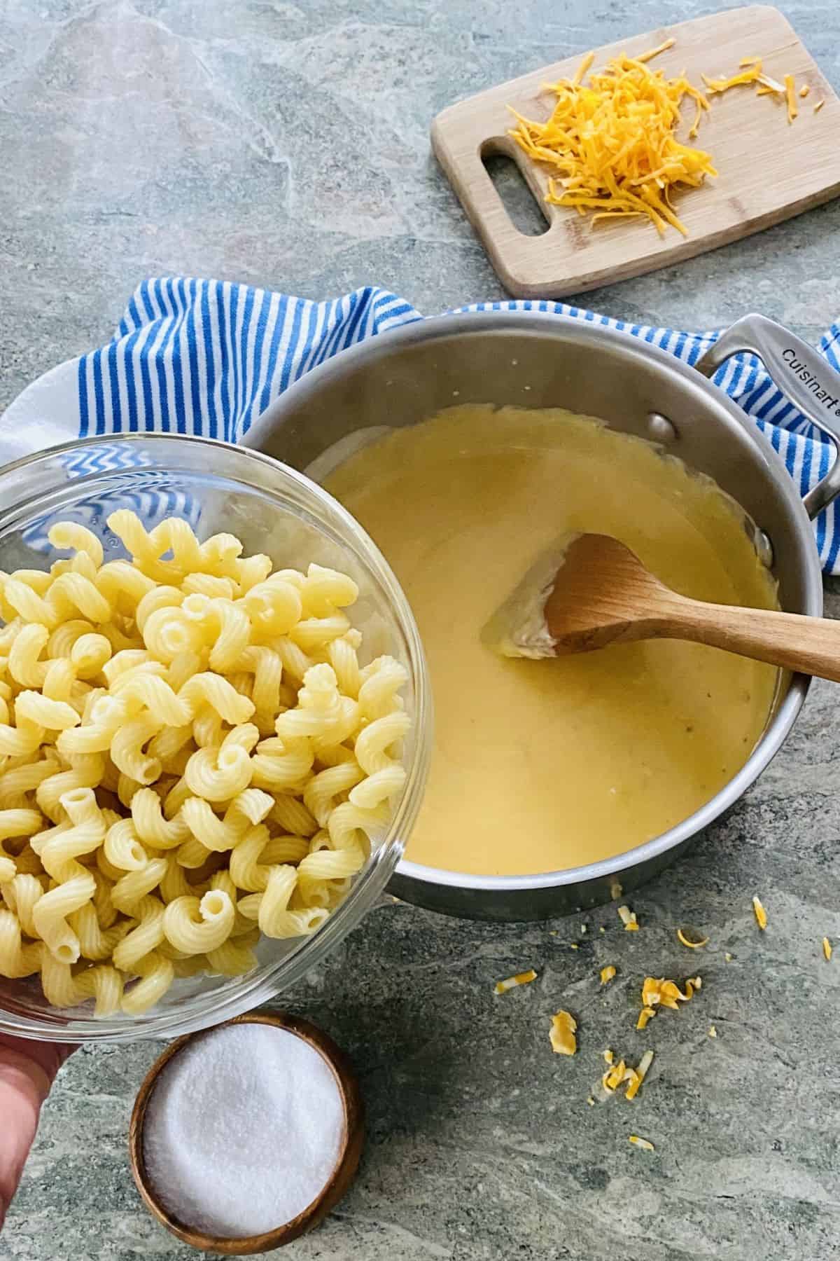 pot with cheese sauce and cooked pasta.